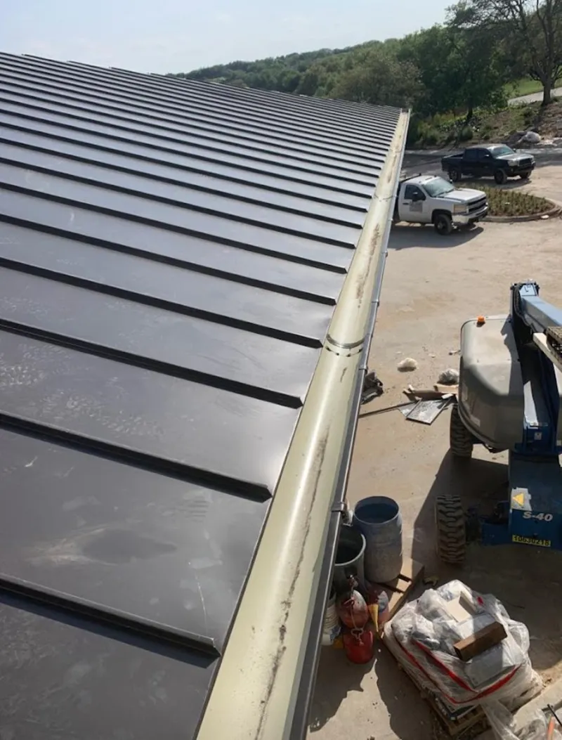 Standing seam panel and gutter detail on a metal roofing jobsite in Camp Swift